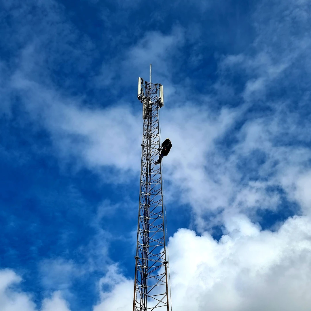 een hoogspanningsmast met een medewerker erin