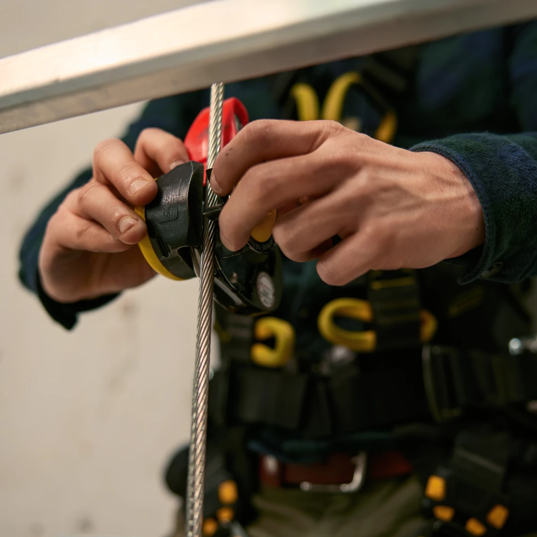 man met handen bij kabel met harnas aan