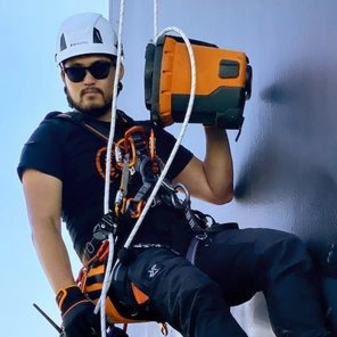 man die aan touwen hangt met afdaal apparaat