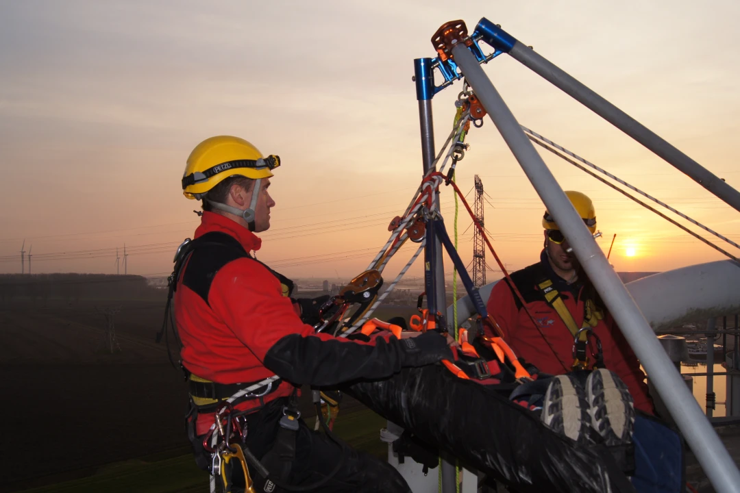 mannen op hoogte met harnas en helm op en man in brancard