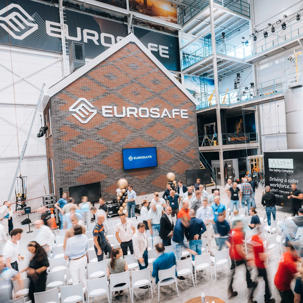 Een huis die staat in een trainingshal waarbij er personen rondlopen