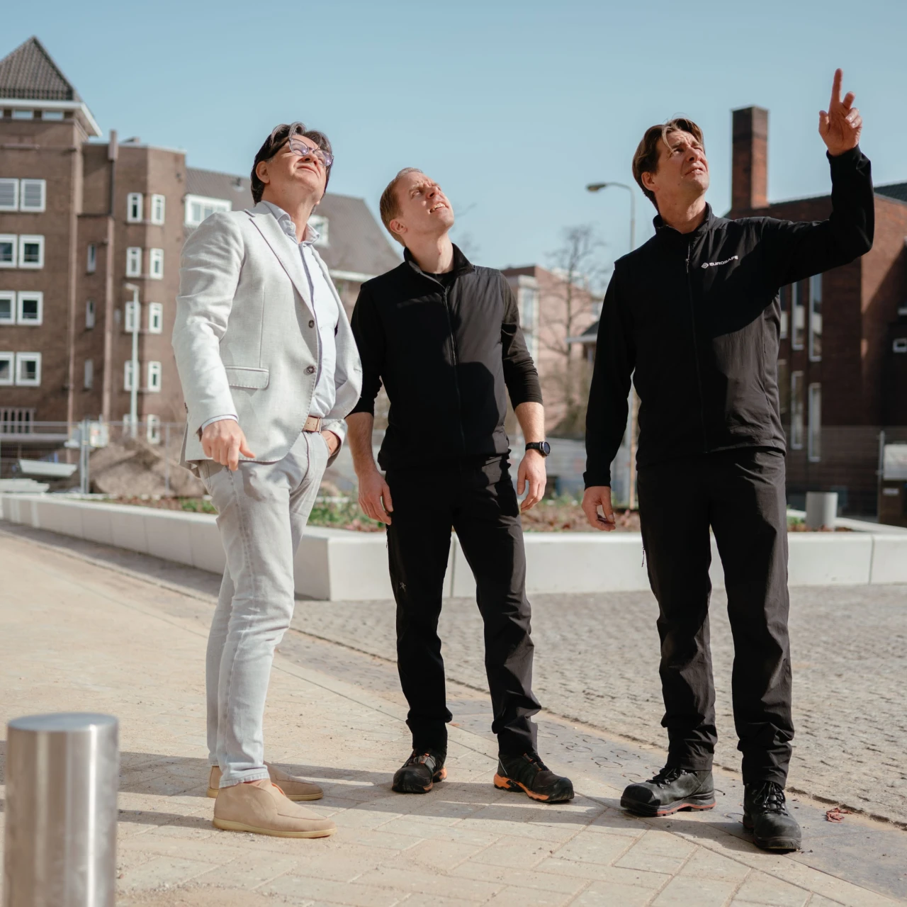 drie mannen wijzen naar boven en kijken naar boven