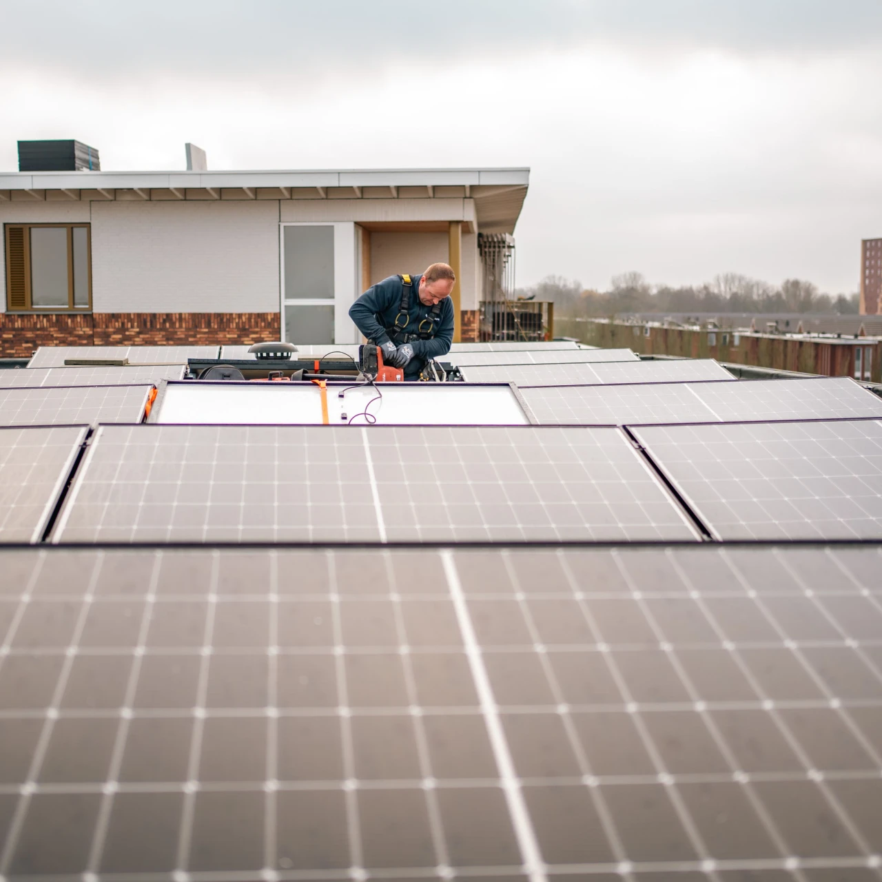 een man die zonnepanelen monteert op een plat dak