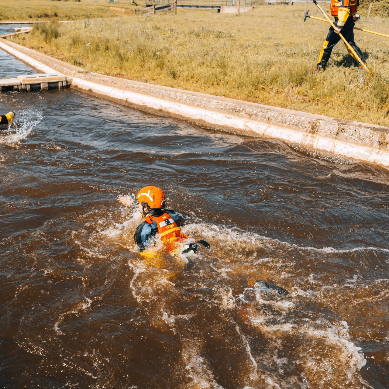 drie personen in snel stromend natuurwater die zichzelf proberen te redden