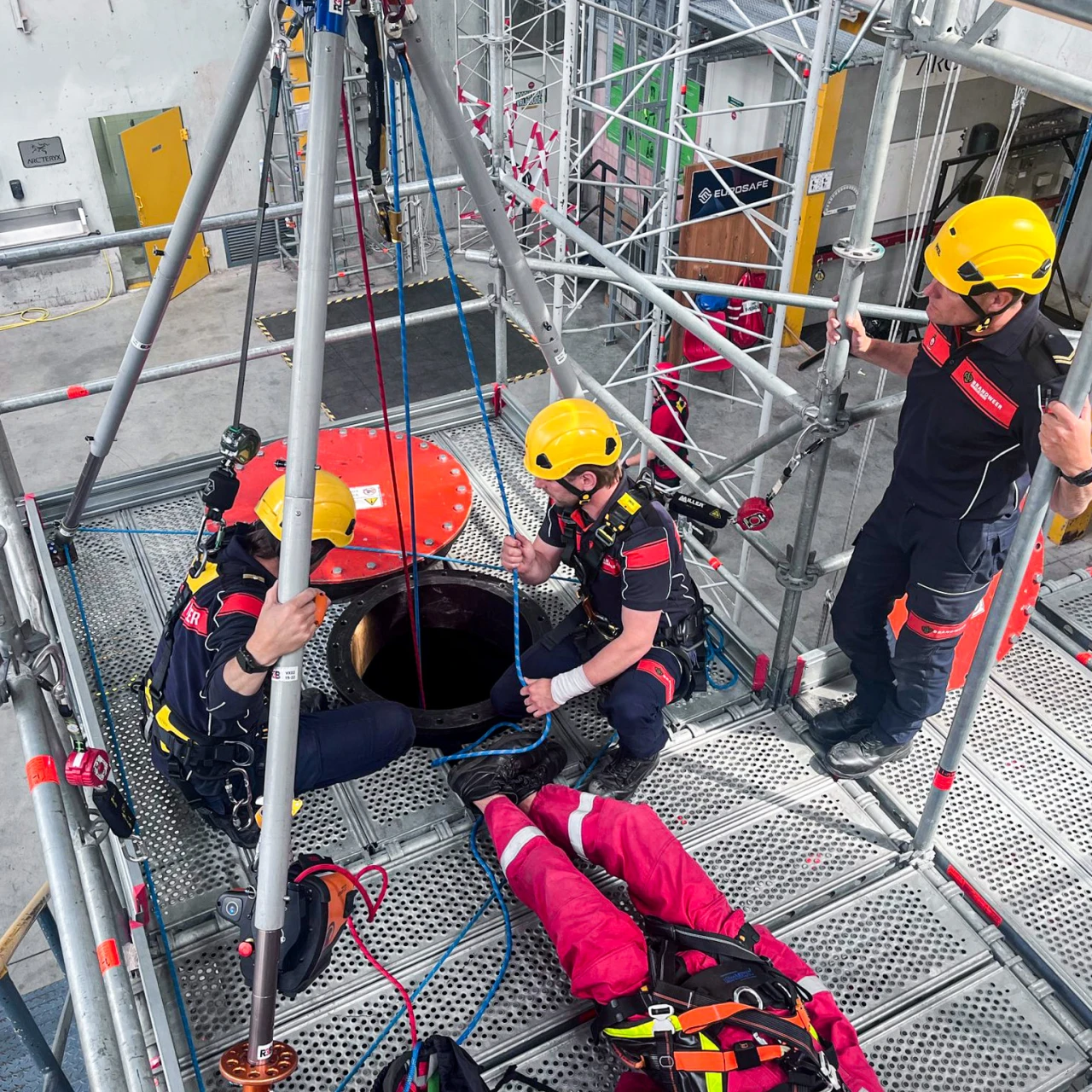 een aantal personen met een shirt aan van de marine brandweer die om een besloten ruimte staan om een slachtoffer te redden
