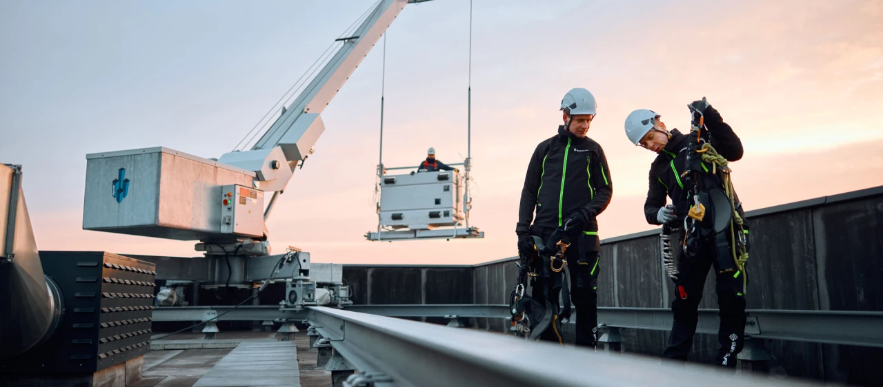 twee mannen op dak met harnas en helm met kraan