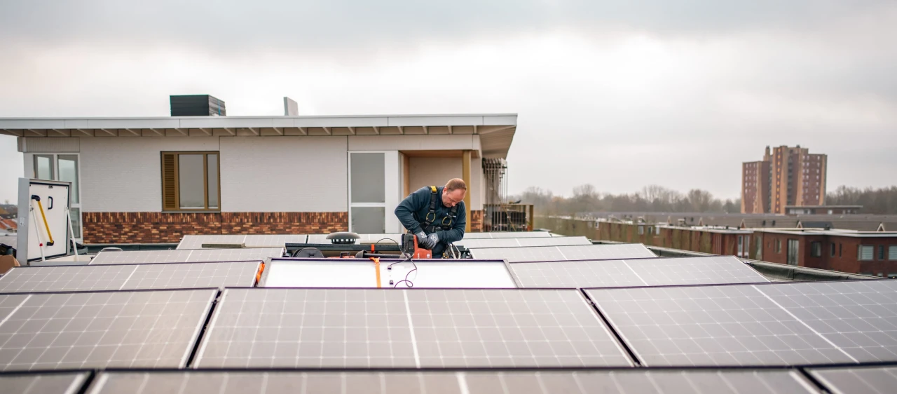 een man die zonnepanelen monteert op een plat dak