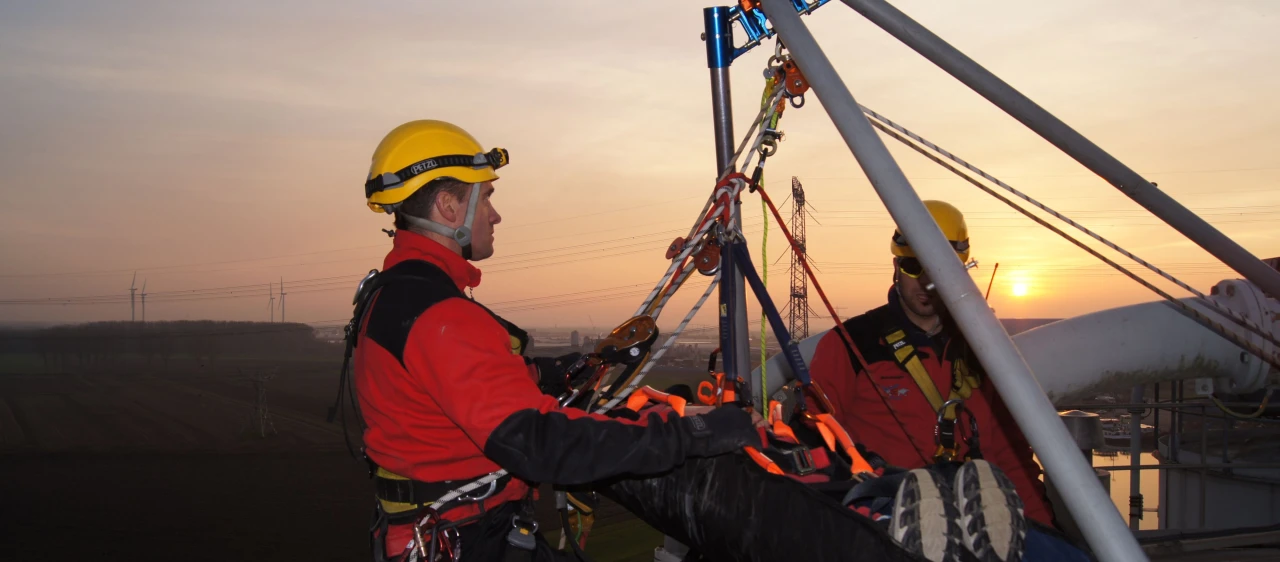 mannen met persoon op brancard op hoogte met harnas aan en helm op