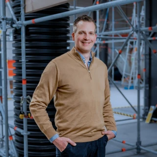 blije man met handen in zakken in loods