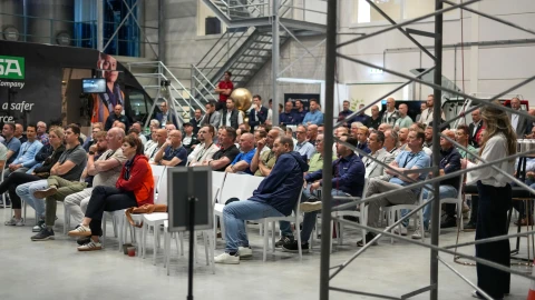 Een groot publiek dat in een zaal zit en luistert naar de talk van de directie