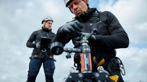 mannen met helm en harnas op dak trekproef valbeveiliging