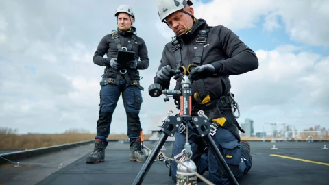 mannen op plat dak met apparatuur en helm op