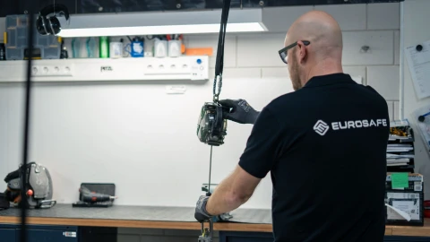 man staat met rug naar camera en houd een valblok vast