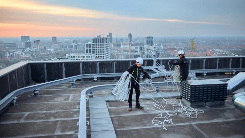 mannen op hoog dak met touw en apparatuur