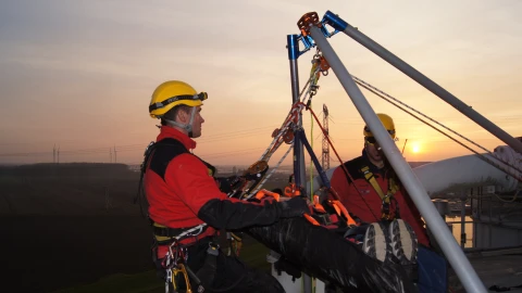 mannen op hoogte met harnas en helm op en man in brancard