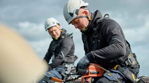 mannen op dak bezig met apparatuur met helm in harnas