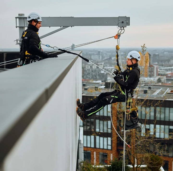 iemand die met een davitsarm langs een gebouw naar beneden abseilt