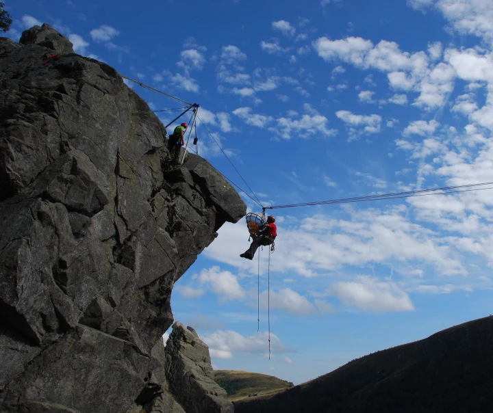 grote rots met man hangend in touw met helm en brancard