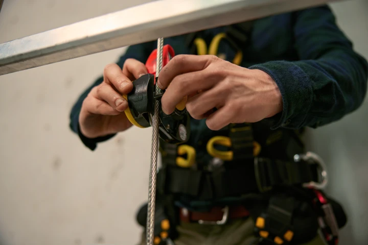 man met handen bij kabel met harnas aan