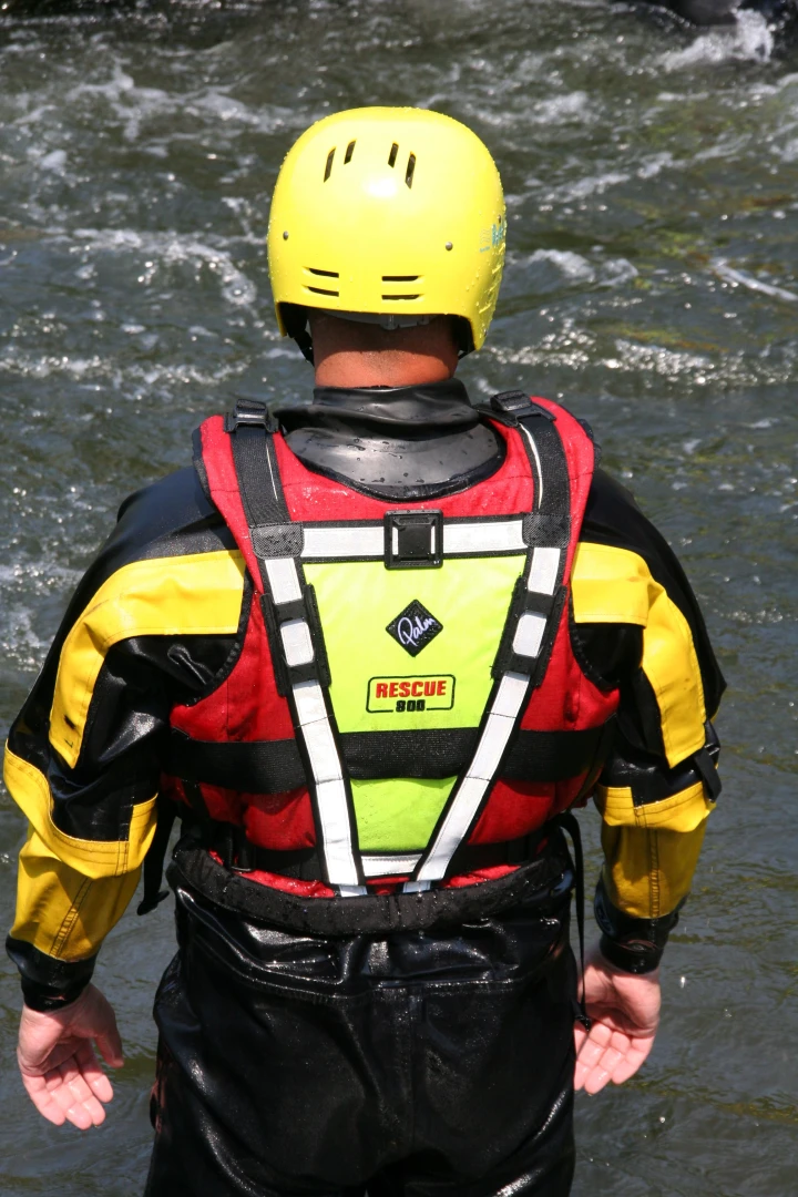 man met reddingsvest en helm bij water