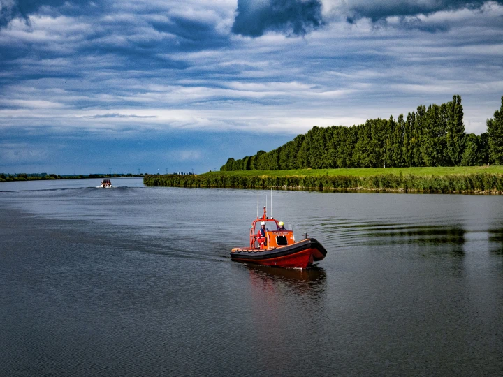 rode boot op water met bomen erachter