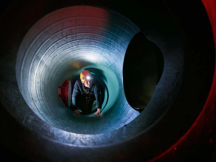 man in besloten ruimte met helm en lamp op hoofd