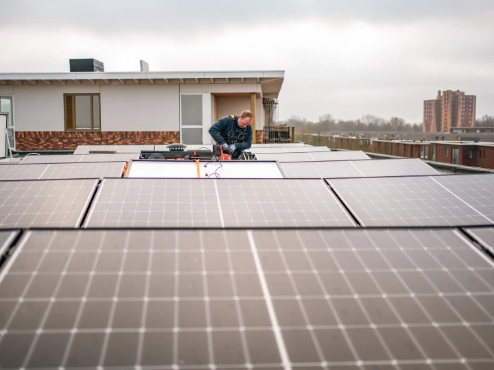 een man die zonnepanelen monteert op een plat dak