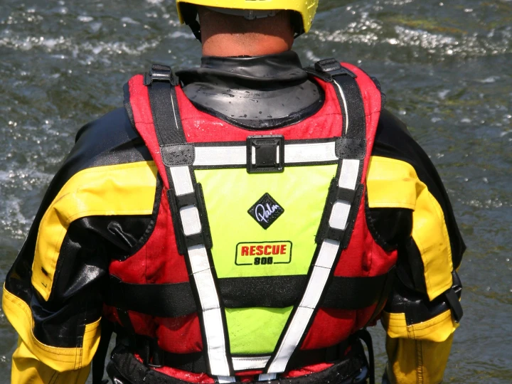 man met reddingsvest en helm bij water