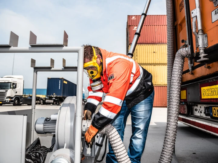 man die met gasmasker op iets aan het meten is met een slang