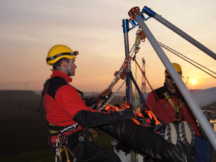 mannen met persoon op brancard op hoogte met harnas aan en helm op