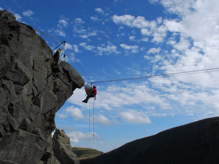mensen bij rots die iemand redden met brancard en touw
