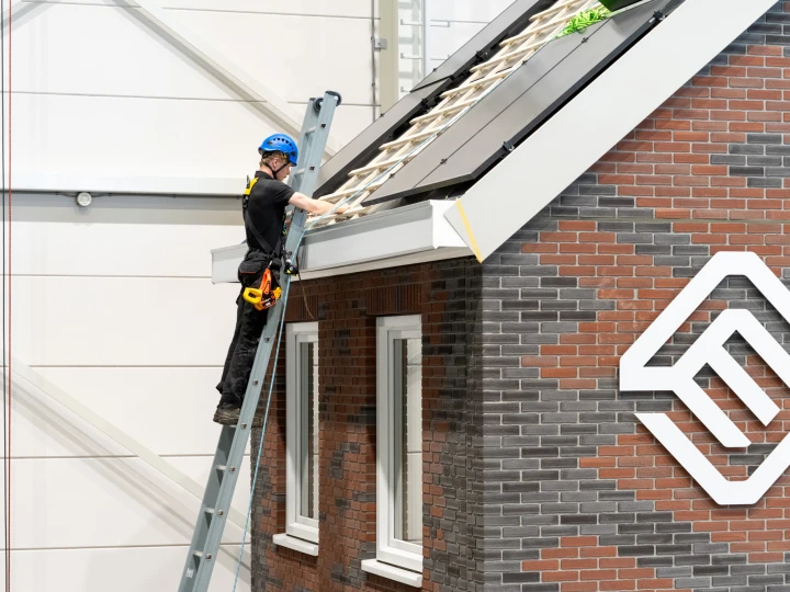 een man die op een ladder staat naast het dak van een woning met zonnepanelen
